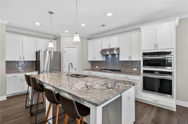 a kitchen with kitchen island a stove a table and chairs in it