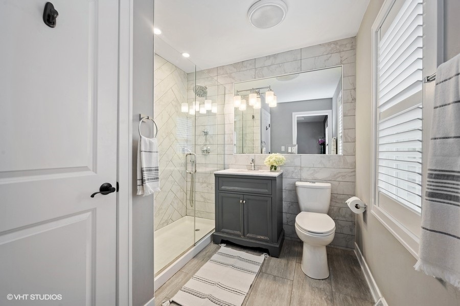111 Riverside Drive Northfield, IL 60093 - Photo 19 of 33 a spacious bathroom with a toilet sink a mirror and a shower
