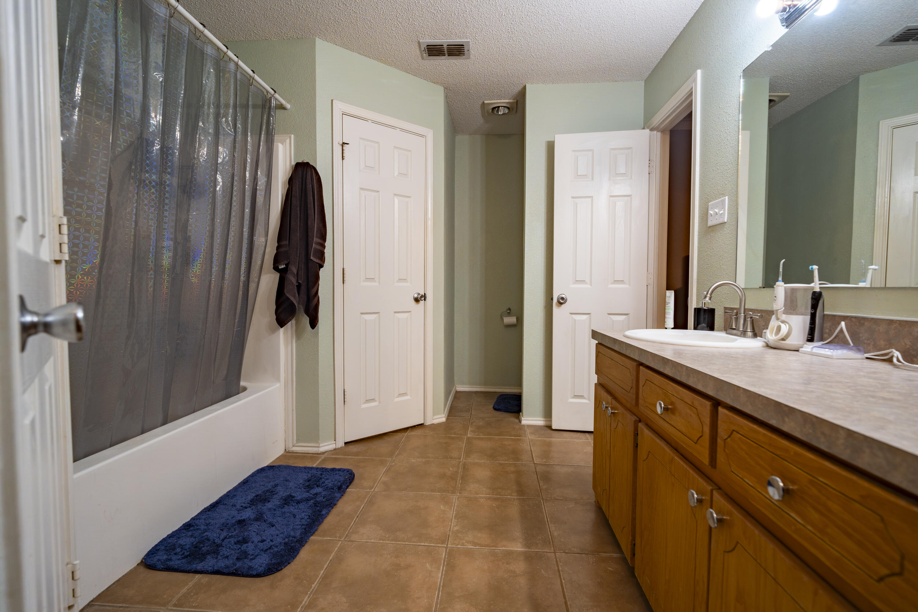 6319 13th Street Lubbock, TX 79416 - Photo 17 of 21 a bathroom with a sink a mirror and a shower