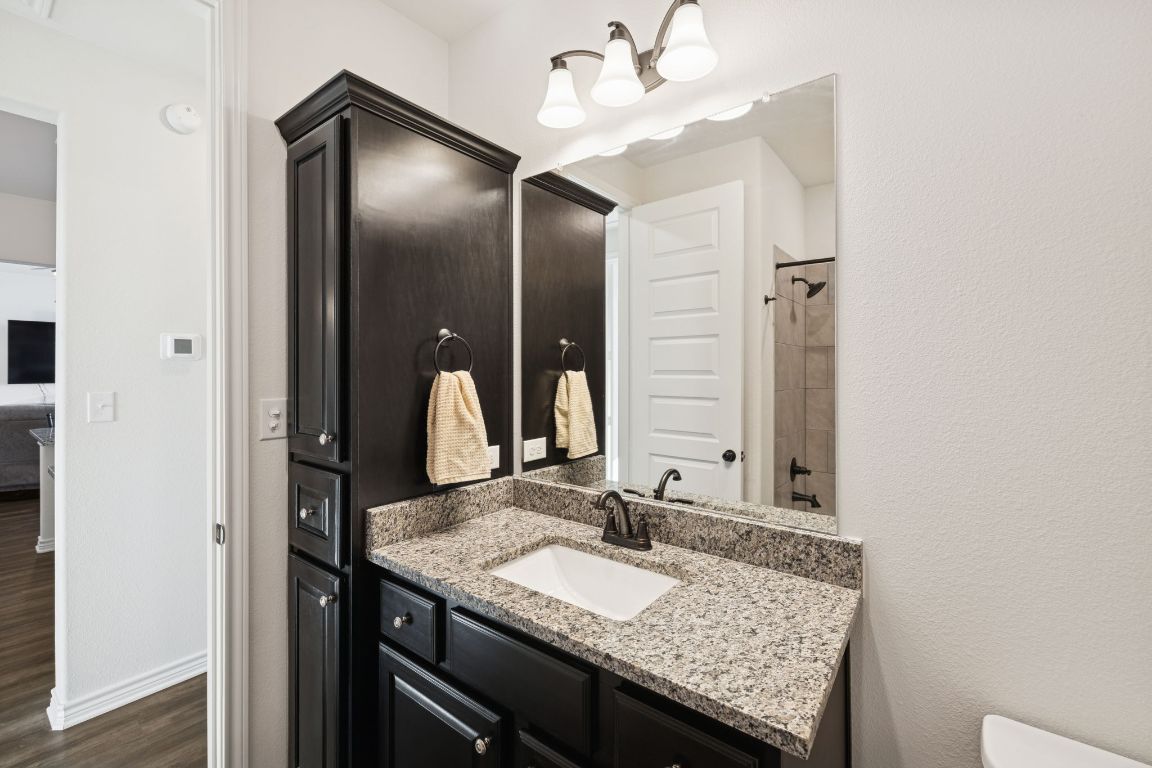108 Santa Teresa Road Kyle, TX 78640 - Photo 17 of 26 a bathroom with a granite countertop sink and a mirror