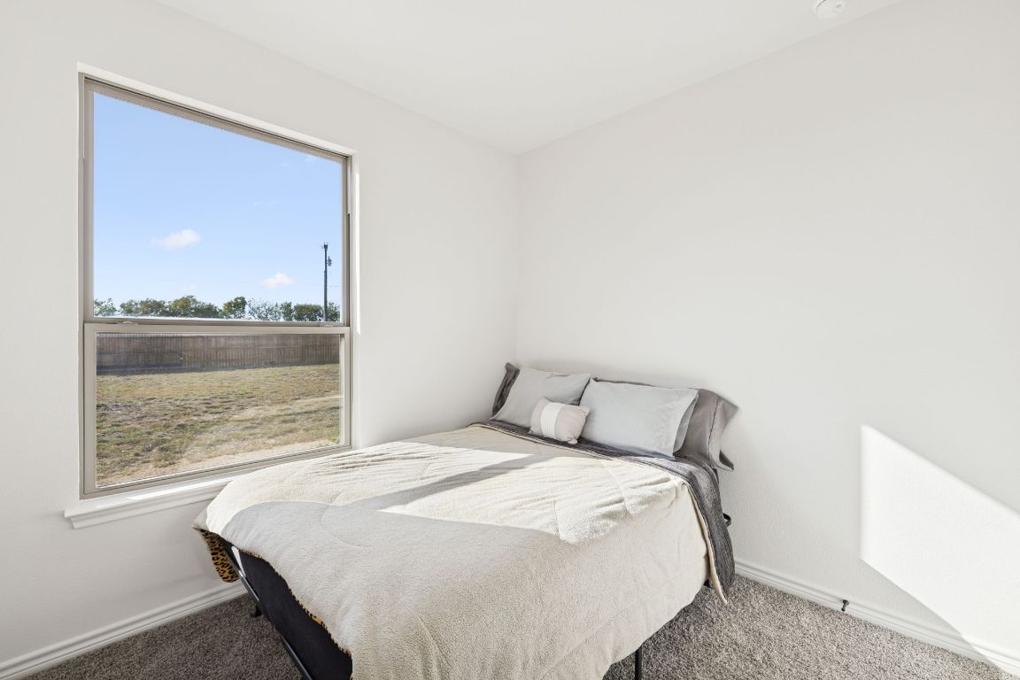 108 Santa Teresa Road Kyle, TX 78640 - Photo 21 of 26 a large bed sitting in a bedroom next to a window