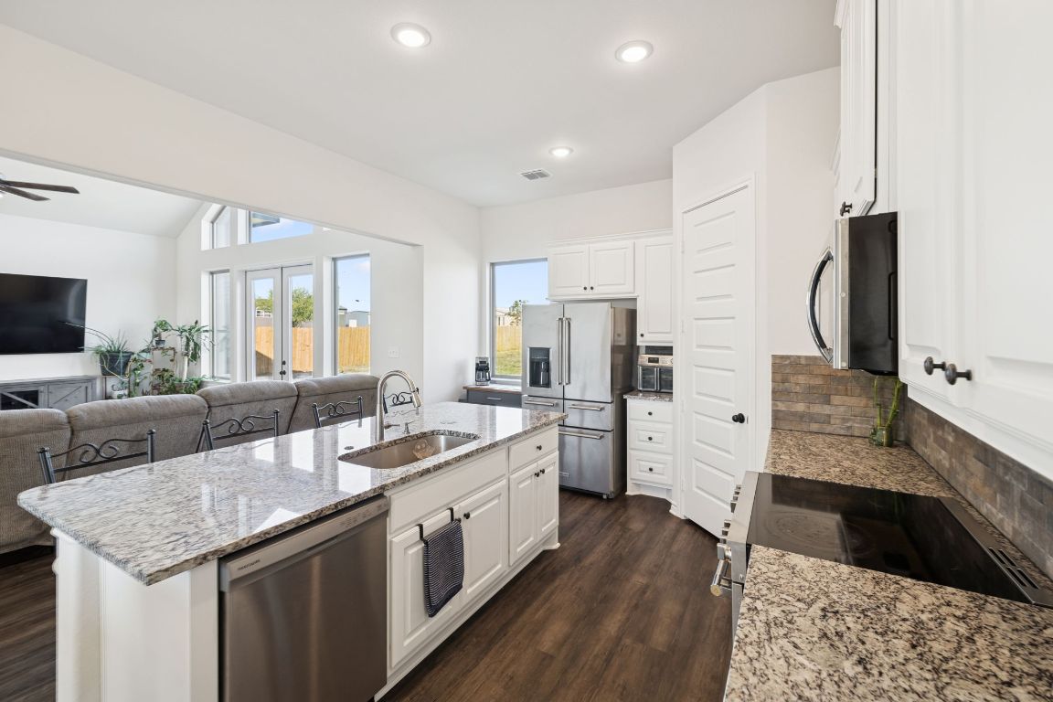 108 Santa Teresa Road Kyle, TX 78640 - Photo 26 of 26 a large kitchen with stainless steel appliances kitchen island granite countertop a stove refrigerator and cabinets
