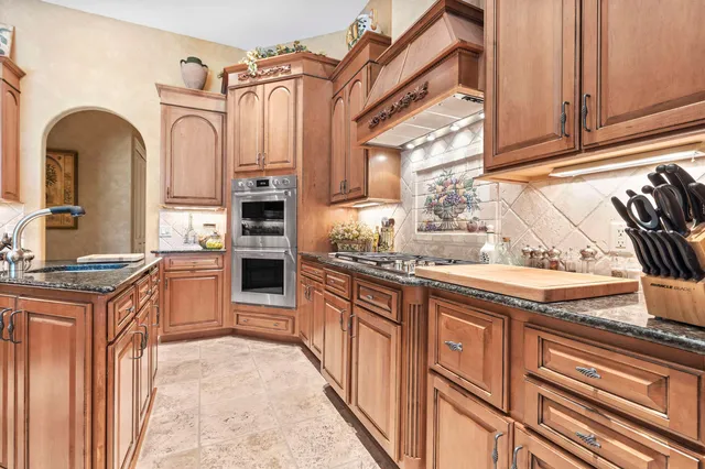 a kitchen with stainless steel appliances granite countertop a sink and a refrigerator