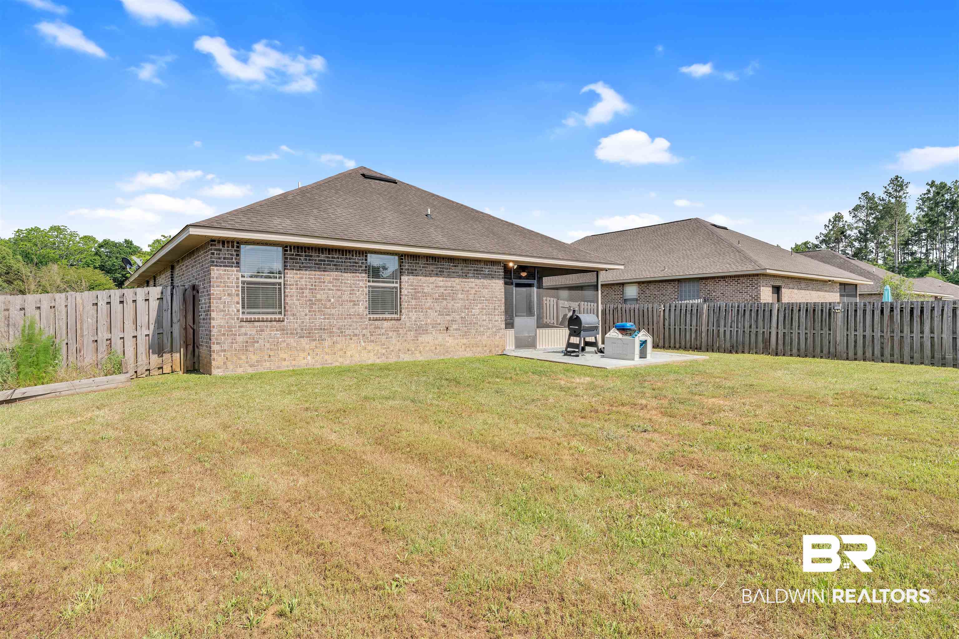 22565 Nana Loop East Silverhill, AL 36576 - Photo 25 of 26 Back of house with roof with shingles, a patio area, brick siding, a fenced backyard, and a lawn
