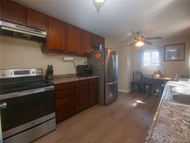 a kitchen with stainless steel appliances granite countertop a stove a sink dishwasher and a refrigerator with wooden floor