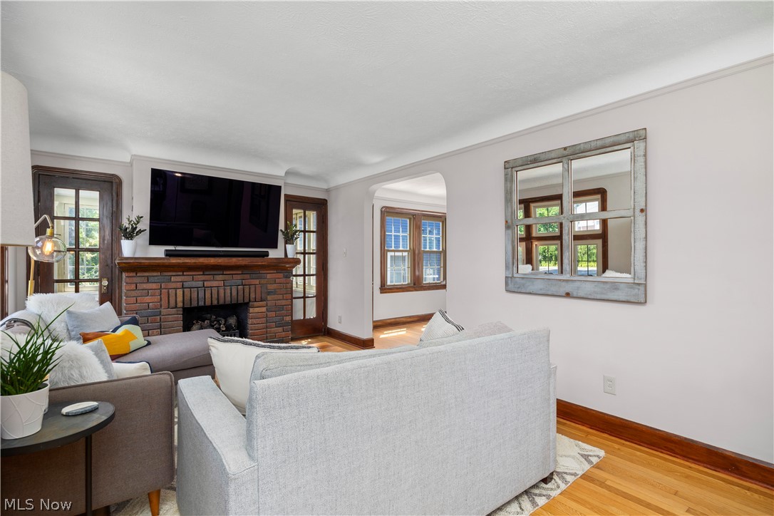 26019 Lake Road Bay Village, OH 44140 - Photo 5 of 40 Living space featuring a brick-surround fireplace with a dark wood mantel, hardwood flooring, and wood-frame doors with glass panels