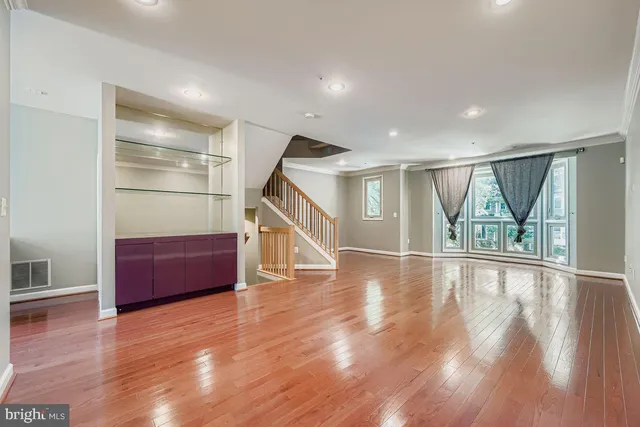 a view of empty room with wooden floor and fan