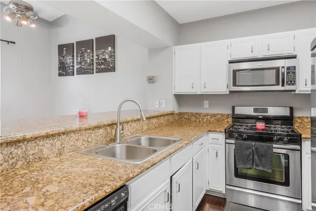 a kitchen with granite countertop a sink stainless steel appliances and cabinets