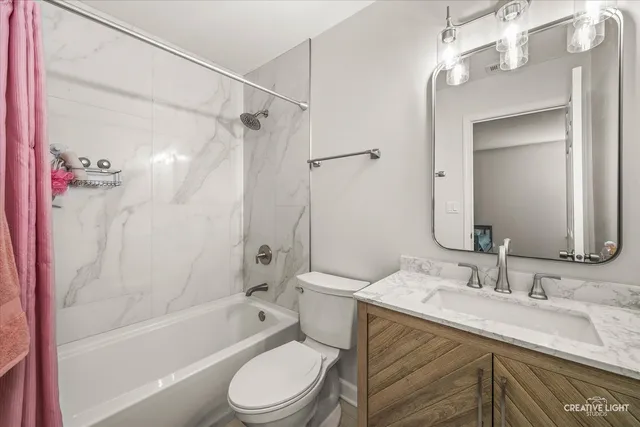a bathroom with a granite countertop sink a toilet a mirror a bathtub and shower