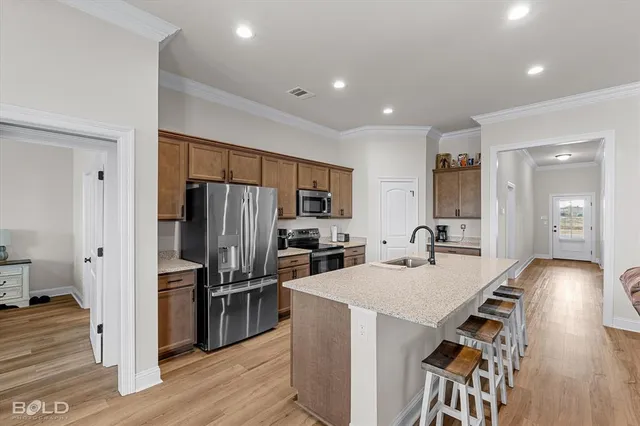 a large kitchen with stainless steel appliances kitchen island granite countertop a refrigerator a sink dishwasher a dining table and chairs with wooden floor