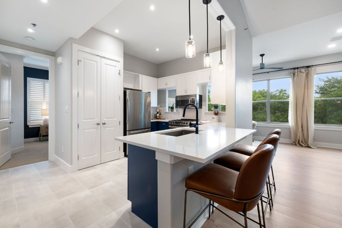 2216 Thornton Road, Unit 431 Austin, TX 78704 - Photo 13 of 30 a large kitchen with kitchen island a large counter top space a sink stainless steel appliances and cabinets