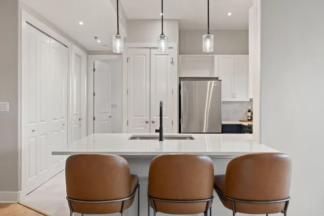 a kitchen with stainless steel appliances granite countertop a table chairs and a refrigerator