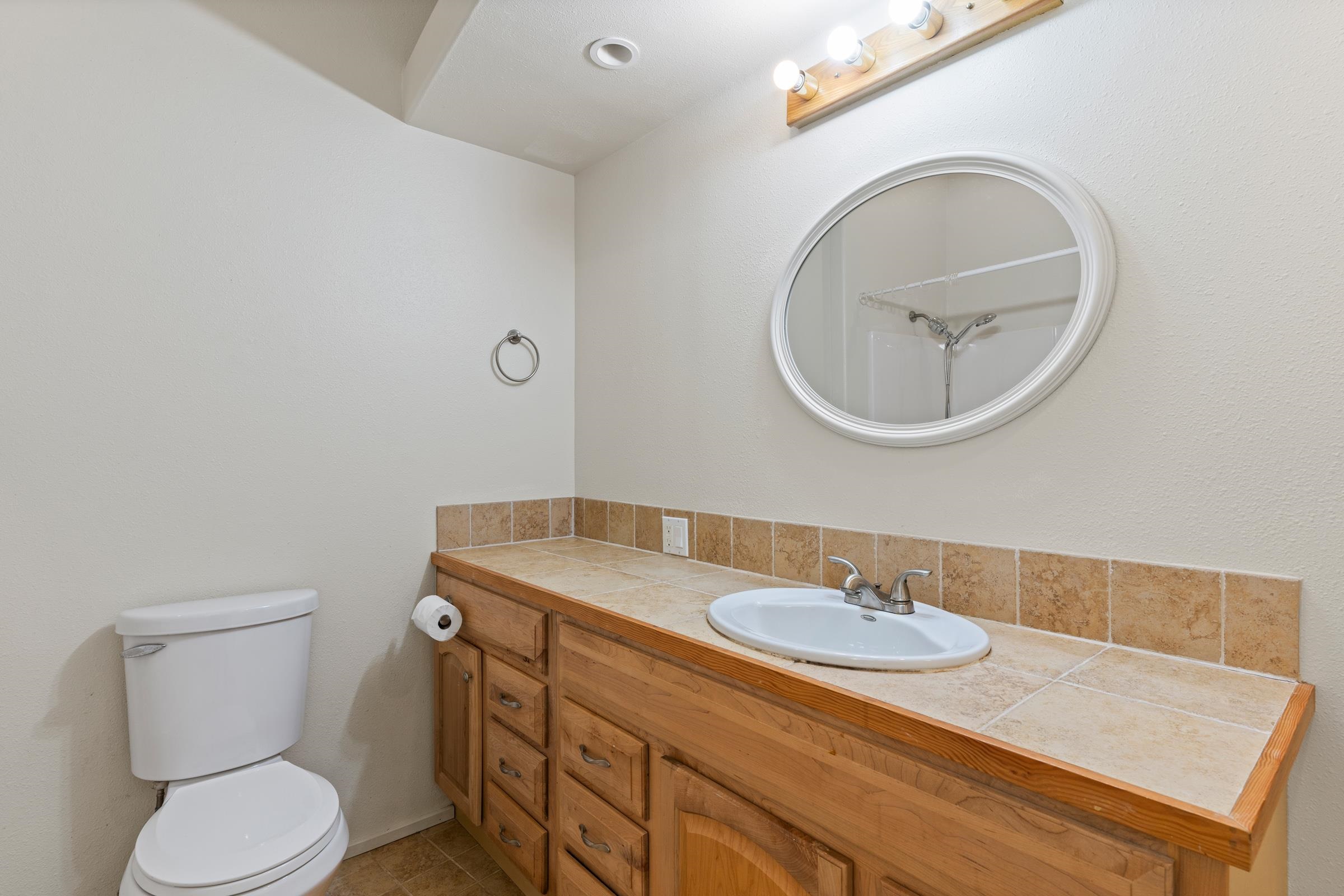 575 Awalau Road Haiku, HI 96708 - Photo 44 of 50 a bathroom with a granite countertop toilet a sink and mirror