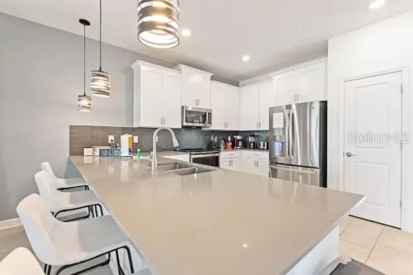 a kitchen with stainless steel appliances granite countertop a refrigerator a stove a sink a dining table and chairs with wooden floor