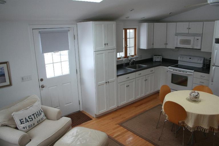 26 Locust Road, Unit 26 Eastham, MA 02642 - Photo 6 of 16 a kitchen with stainless steel appliances granite countertop a sink dishwasher and white cabinets with wooden floor