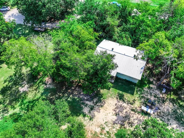 an aerial view of a house with a yard and trees all around