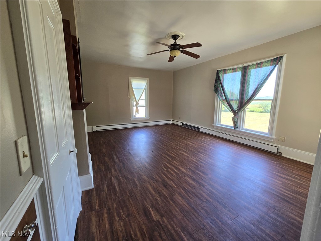 5555 Detroit Road Sheffield, OH 44054 - Photo 5 of 50 Unfurnished living room with dark wood finished floors, a ceiling fan, and baseboard heating