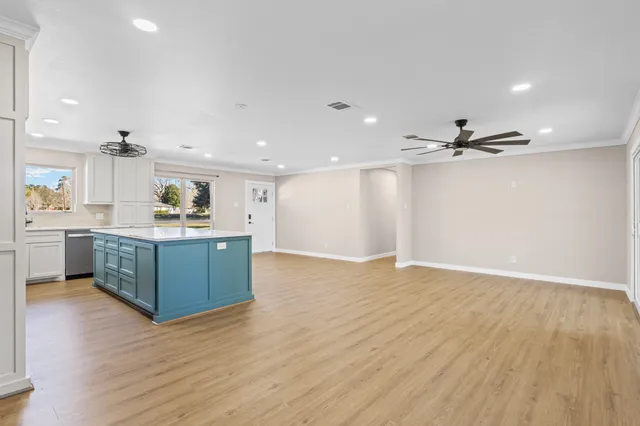 a kitchen with kitchen island a sink wooden floor and white stainless steel appliances