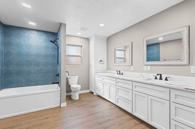 a bathroom with a double vanity sink a toilet and a large mirror