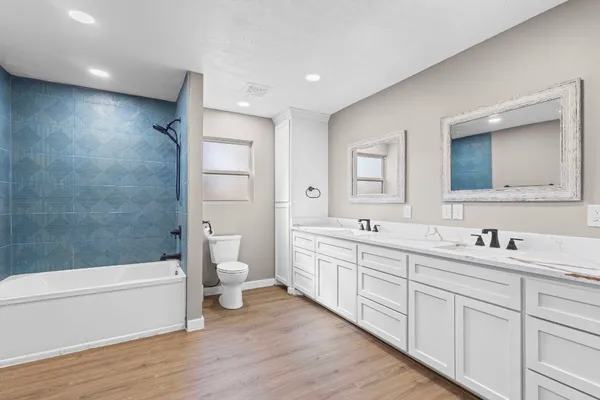 a bathroom with a double vanity sink a toilet and a large mirror