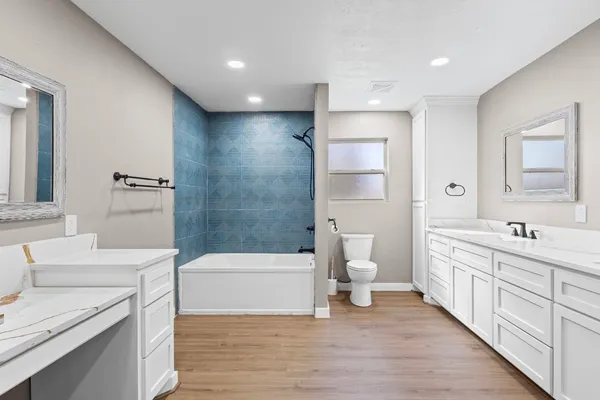 a bathroom with a double vanity sink a toilet and a tub