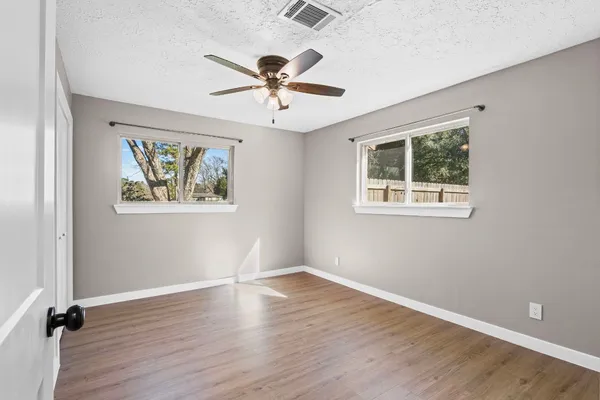 a view of empty room with wooden floor and fan