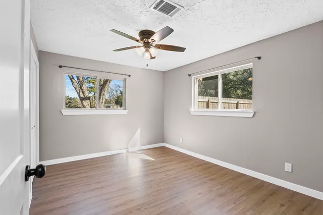 a view of empty room with wooden floor and fan
