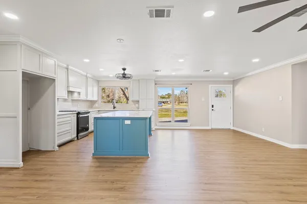 a large kitchen with stainless steel appliances granite countertop a large counter top a sink and a refrigerator