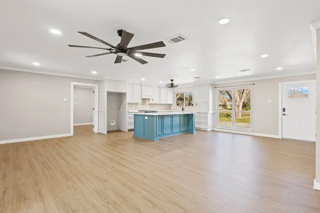 a view of an empty room with window and wooden floor