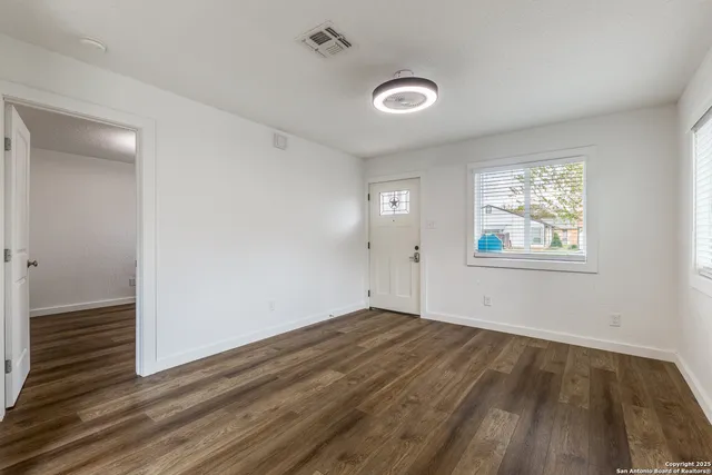 an empty room with wooden floor and windows