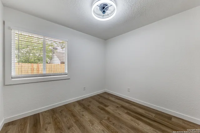a view of a room that has wooden floor and a window