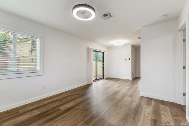 an empty room with wooden floor and windows