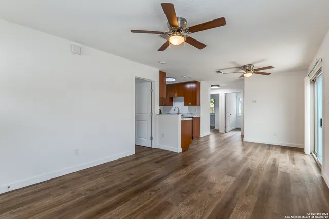 a view of a kitchen with a sink a refrigerator a ceiling fan and wooden floor