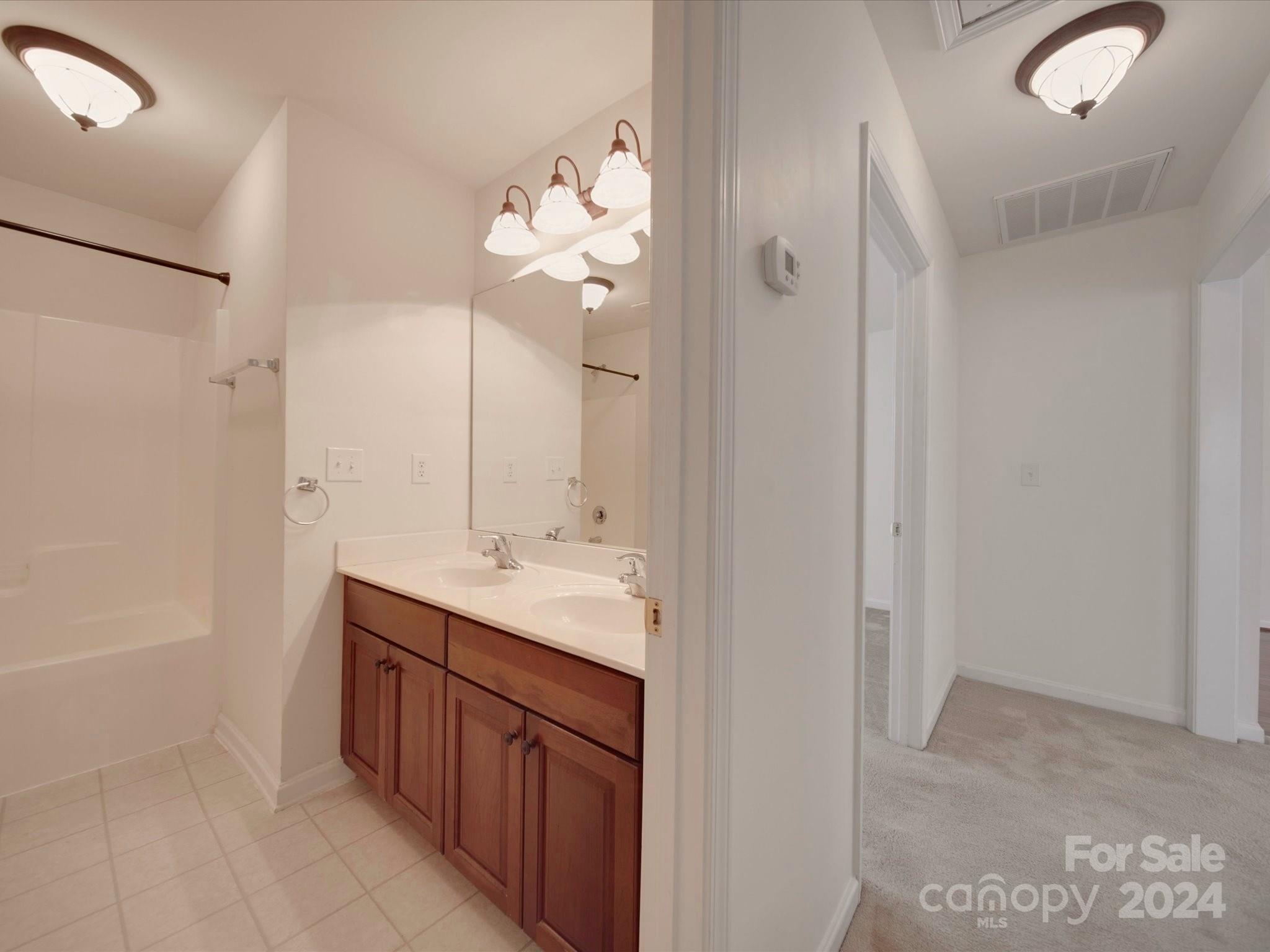 1004 Spanish Moss Road Indian Trail, NC 28079 - Photo 8 of 25 a bathroom with a double vanity sink and mirror with shower