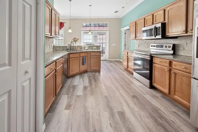 a kitchen with stainless steel appliances granite countertop a refrigerator a stove top oven a sink dishwasher and wooden floor