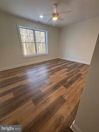 an empty room with wooden floor fan and windows
