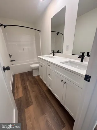 a spacious bathroom with a double vanity sink toilet mirror and shower