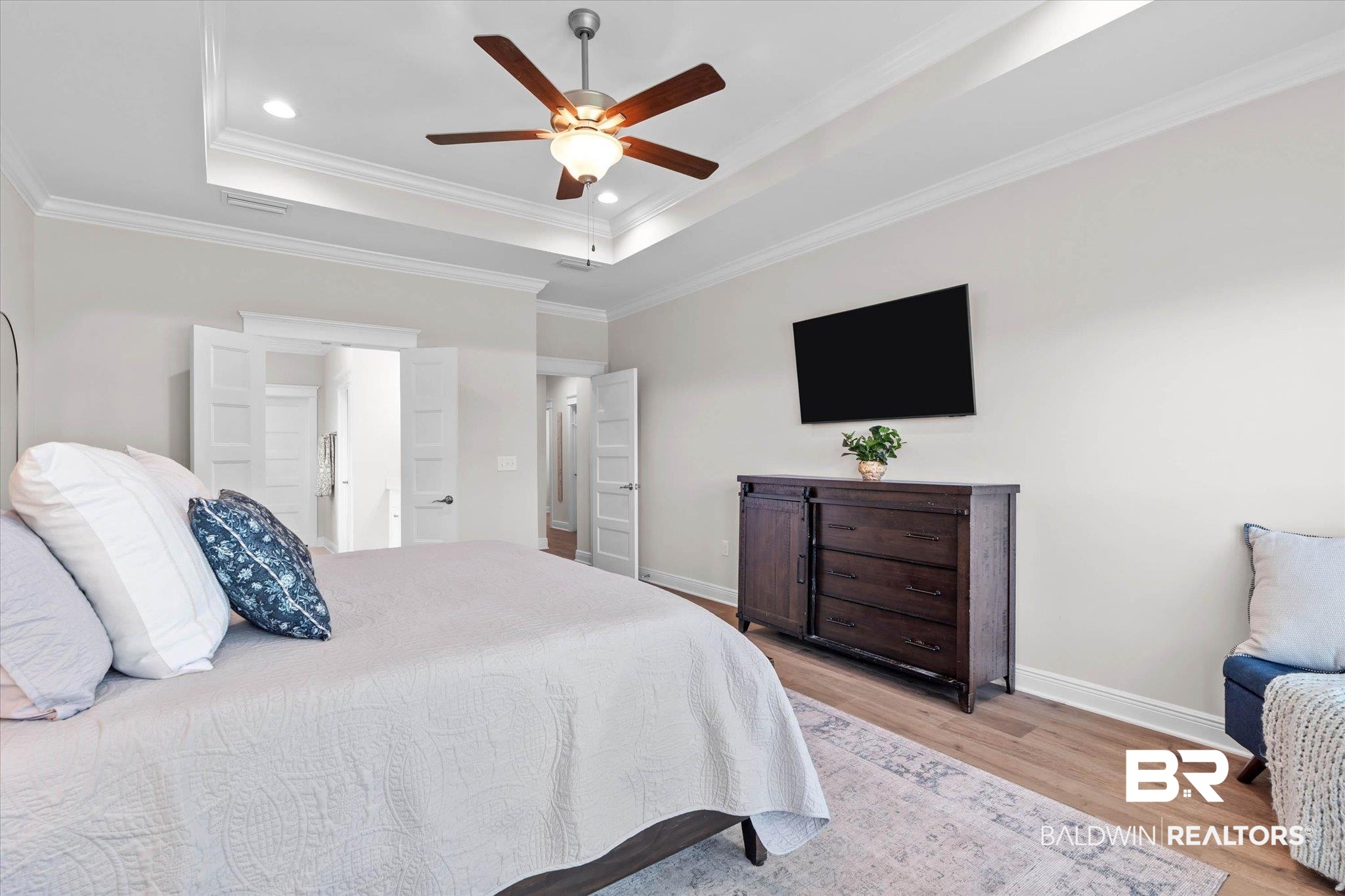 23523 Travis Stock Street Foley, AL 36535 - Photo 16 of 45 Spacious bedroom featuring a tray ceiling with recessed lighting, wood-finish flooring, crown molding, and double white paneled doors