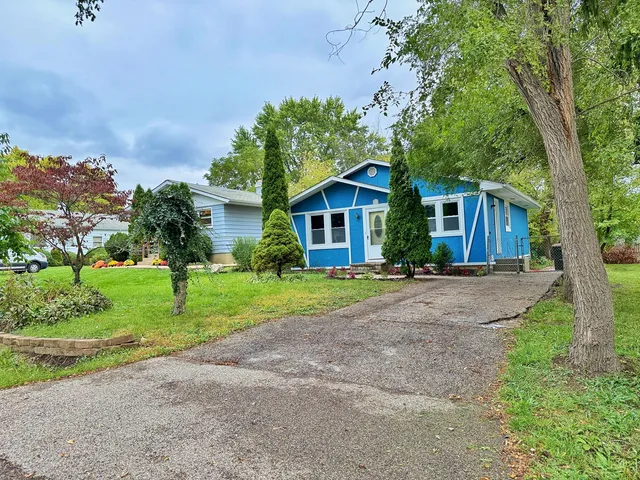 a view of a house with a yard and large trees