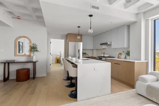 a kitchen with kitchen island stainless steel appliances a stove a sink a refrigerator a center island and a fireplace