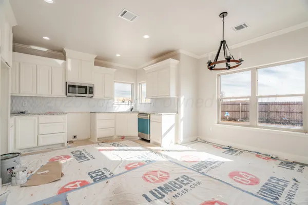 a open kitchen with kitchen island white cabinets and stainless steel appliances