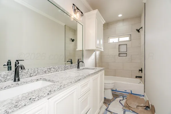 a bathroom with a granite countertop sink a toilet and shower