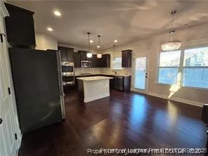 a open kitchen with stainless steel appliances granite countertop a refrigerator a sink dishwasher a stove and a large refrigerator with wooden floor