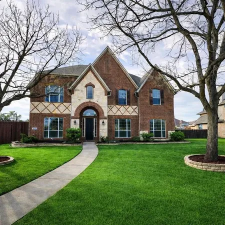 a front view of a house with a garden and trees
