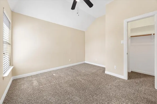 an empty room with ceiling fan and window