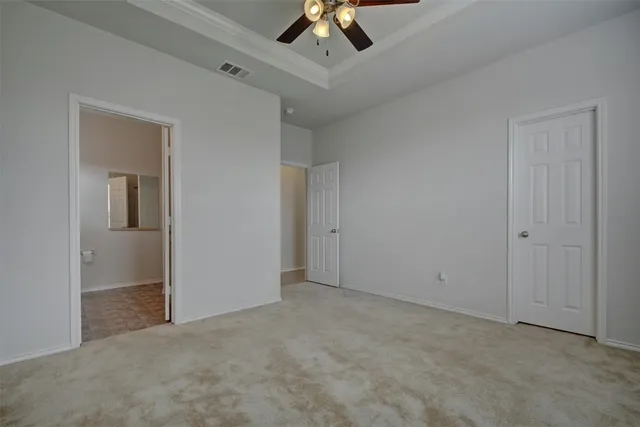 an empty room with a ceiling fan and carpet