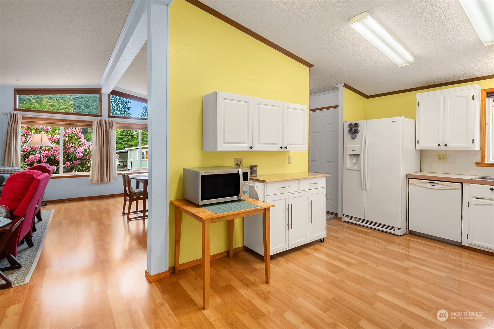 5810 Fleming Street, Unit 33 Everett, WA 98203 - Photo 8 of 28 a kitchen with a refrigerator a stove top oven and a dining table with wooden floor