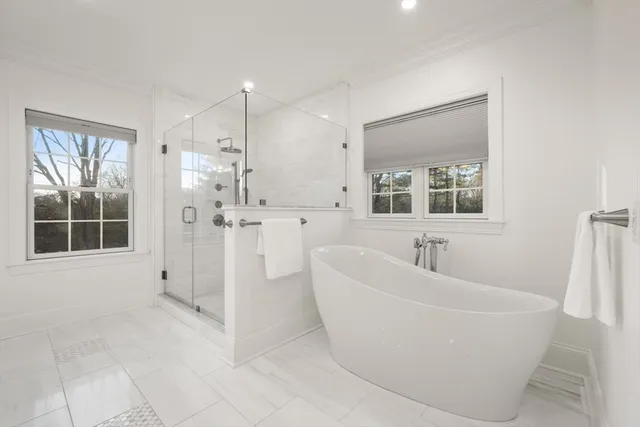 a white bath tub sitting in a bathroom and mirror