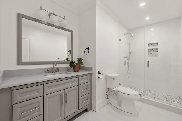 a bathroom with a toilet a sink a mirror a shower and vanity