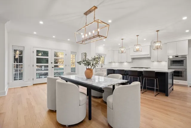 a dining room with kitchen island stainless steel appliances furniture a chandelier and kitchen view
